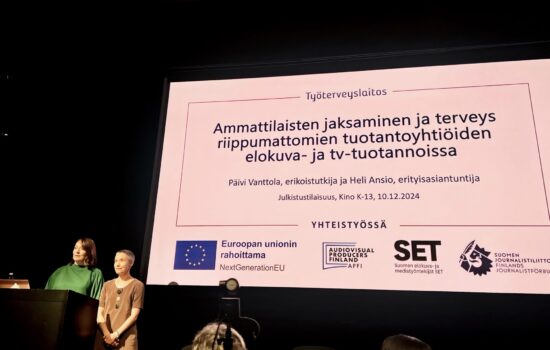 Työterveyslaitoksen tutkijat Päivi Vanttola ja Heli Ansio. seisovat presentaation edessä.